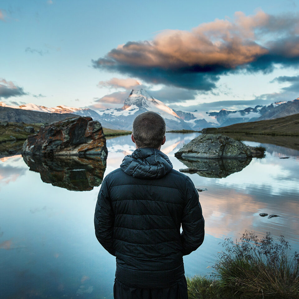 Man from Back Looking at a Lake in the Montains